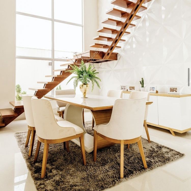 Modern Dining room with white upholstery and wood chairs and table. A floating wooden staircase and large windows are behind. 