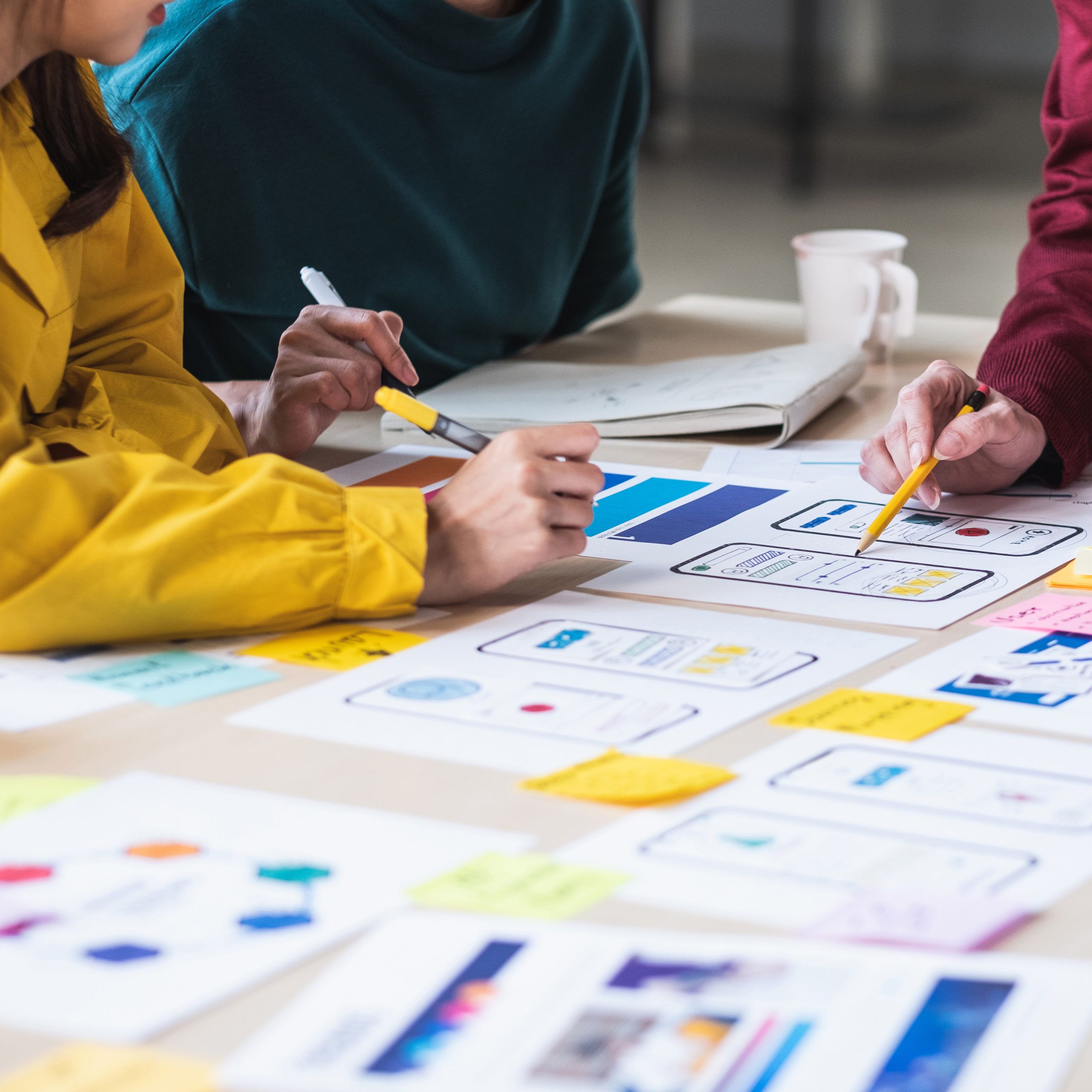 Close up look at agency working on UX design, with many colorful designs/charts on table